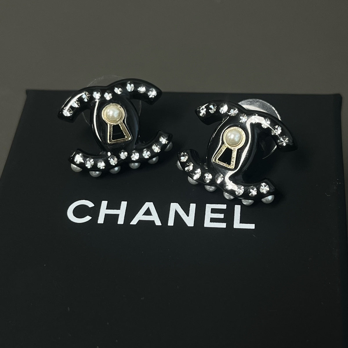Chanel - Other - Gold-tone metal details with rhinestones, pearl and black resin elements; exact composition not confirmed. - Black